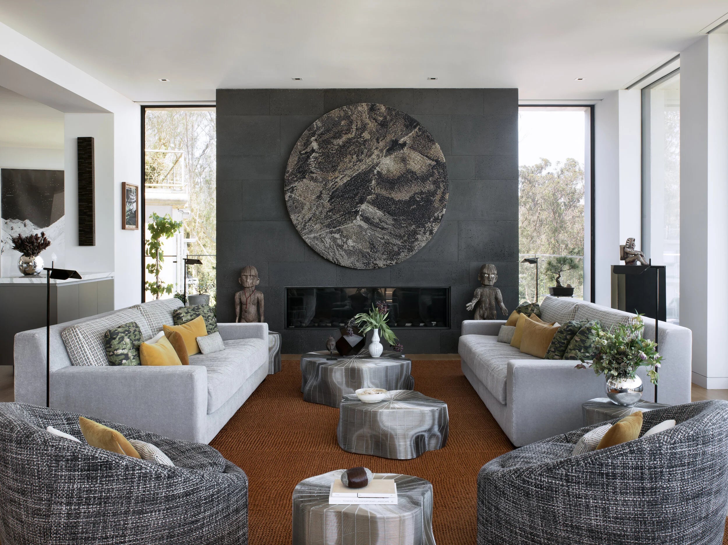 Modern living room with gray sofas, decorative pillows, and a large circular artwork on the wall.