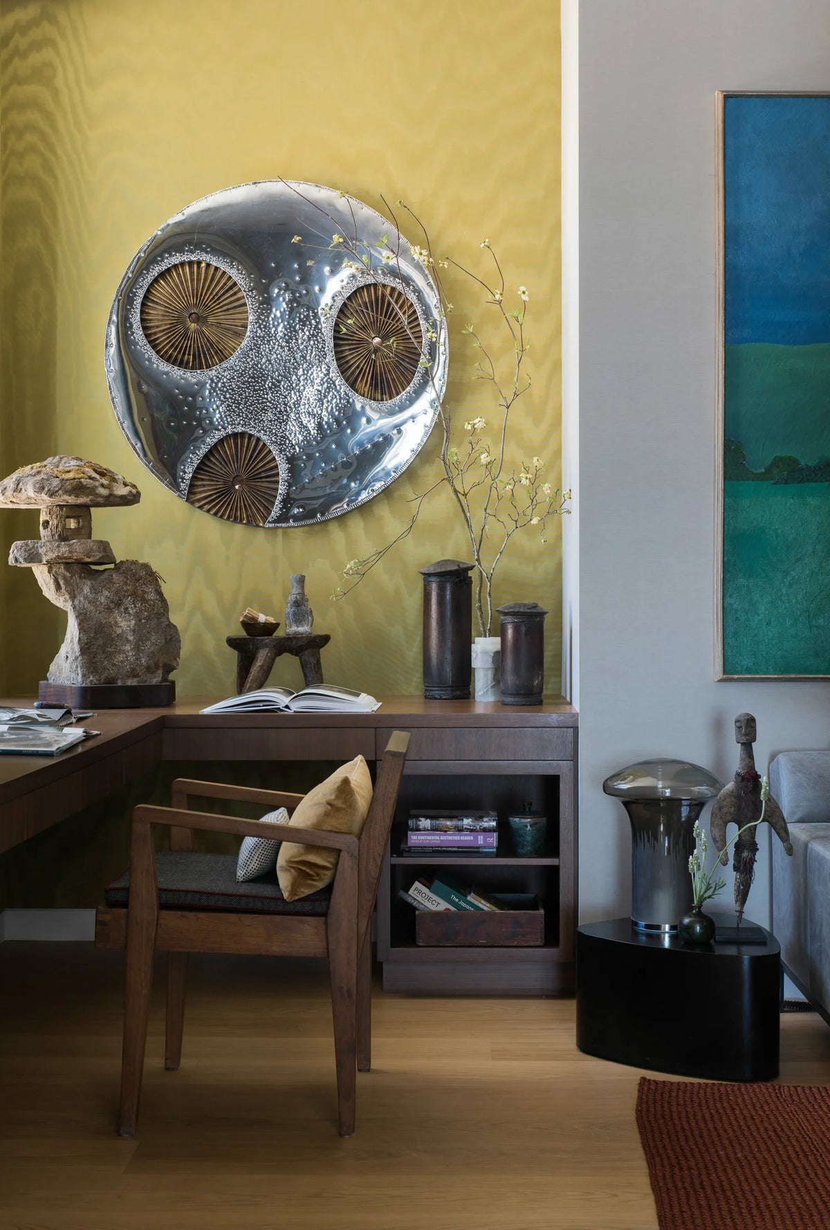 Living room with desk and chair, sculptures, and decorative wall art.