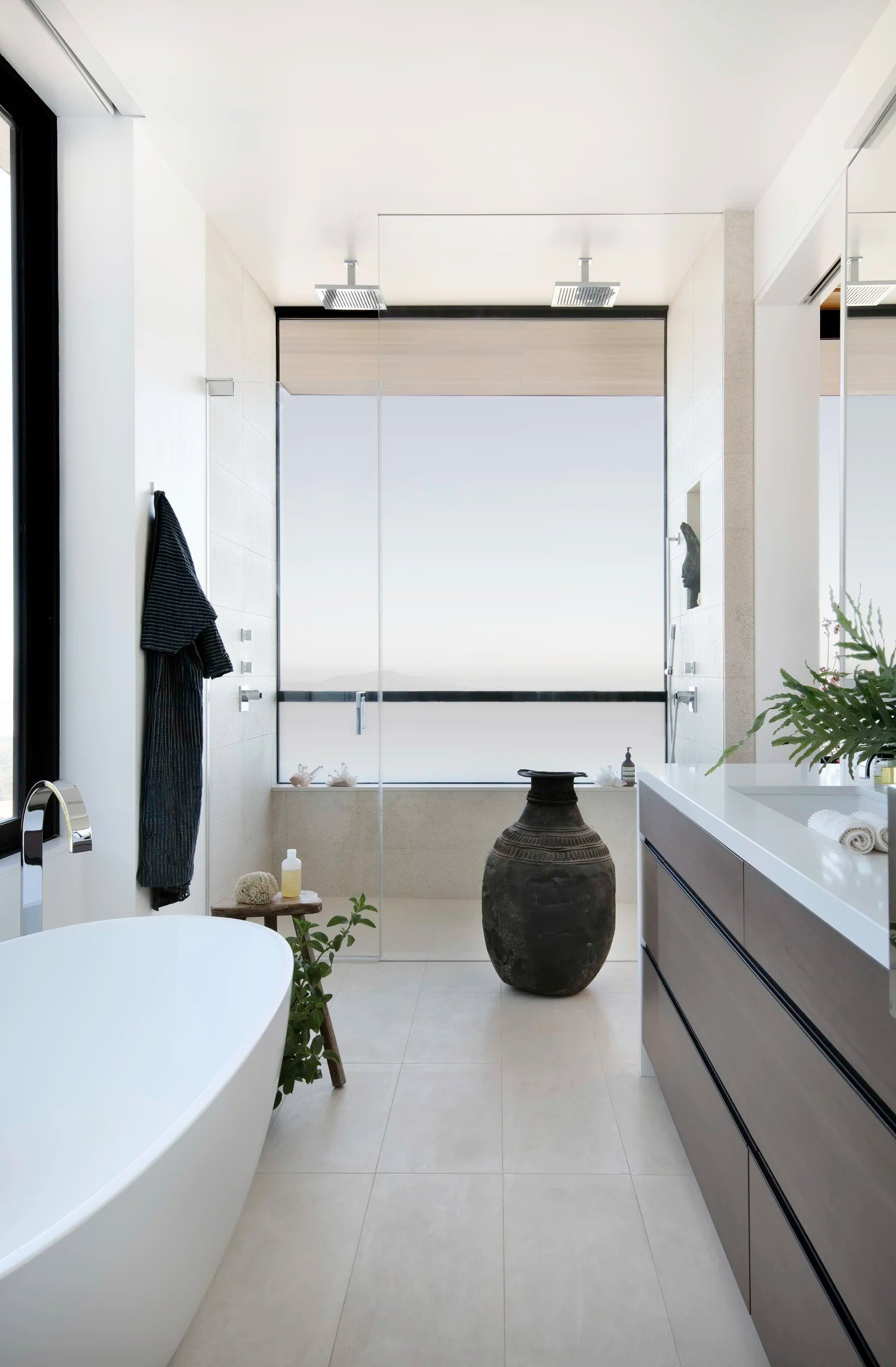 Modern bathroom with a freestanding bathtub, vanity, and decorative vase.