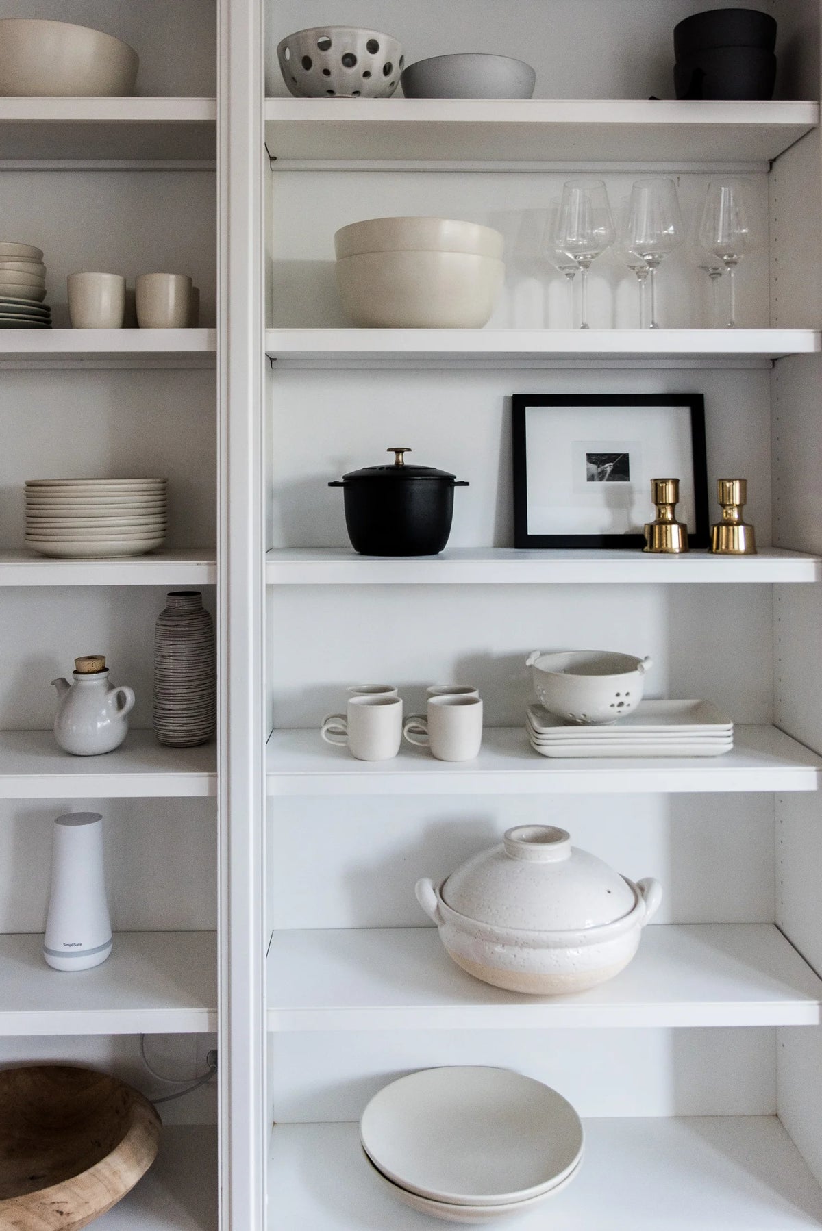 White shelves with various kitchenware including bowls, cups, and a pot.