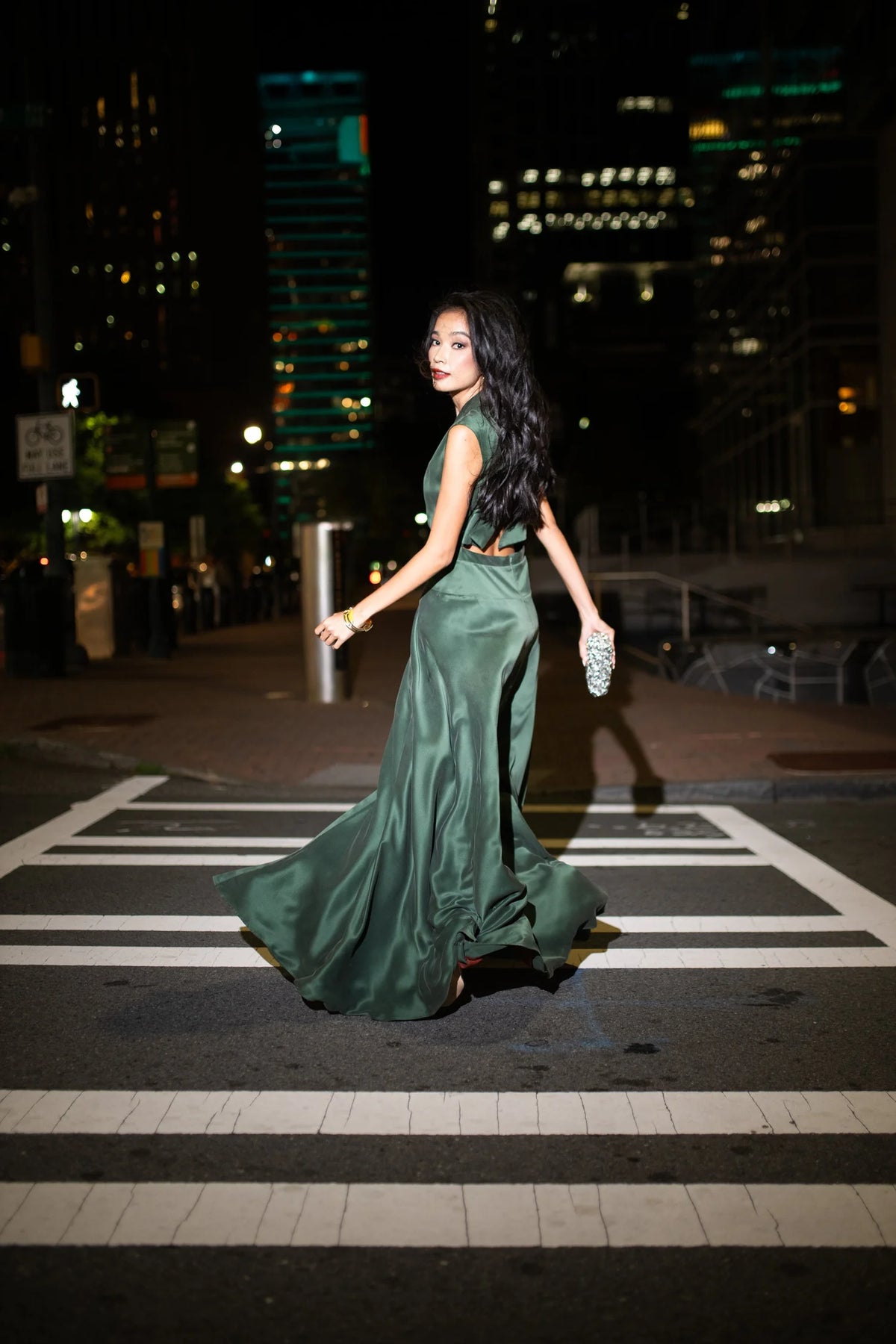 Woman in green evening gown crossing the street in the city at night