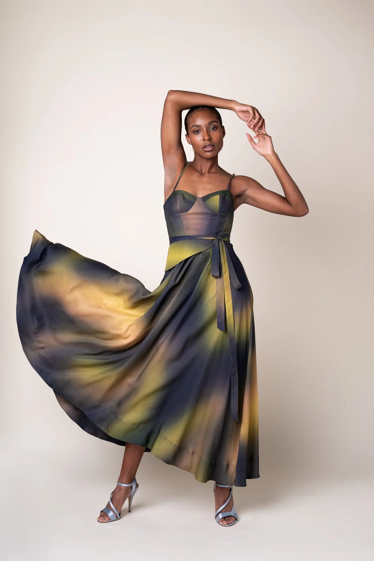 Woman wearing a colorful dress with a flowing skirt on a plain background