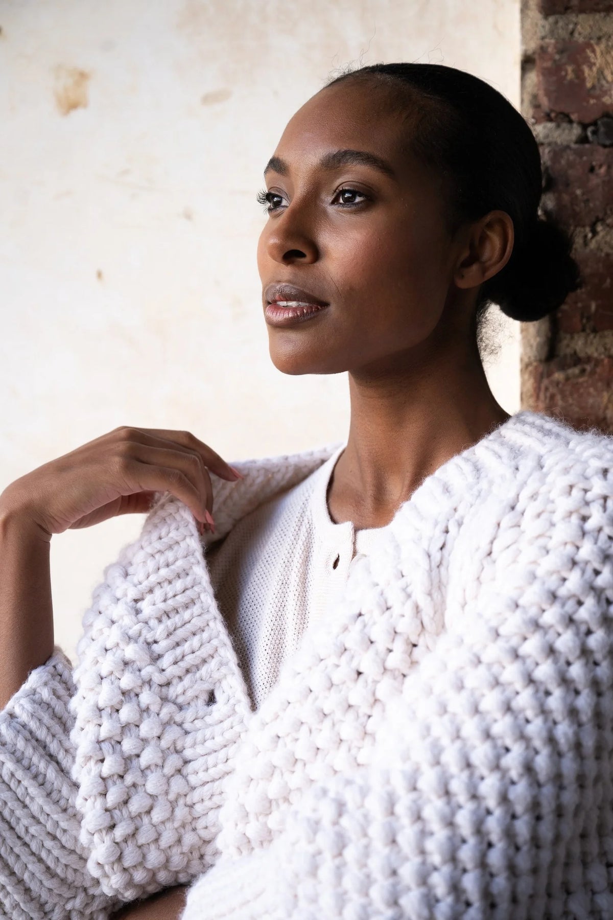 Woman in white chunky sweater looking off in distance