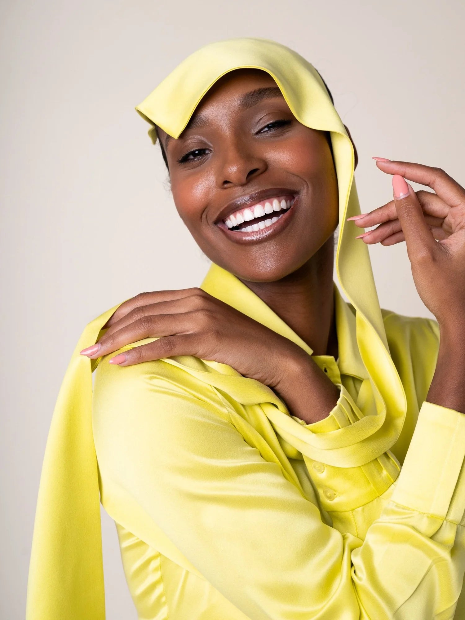 Woman wearing a yellow hijab and outfit against a plain background