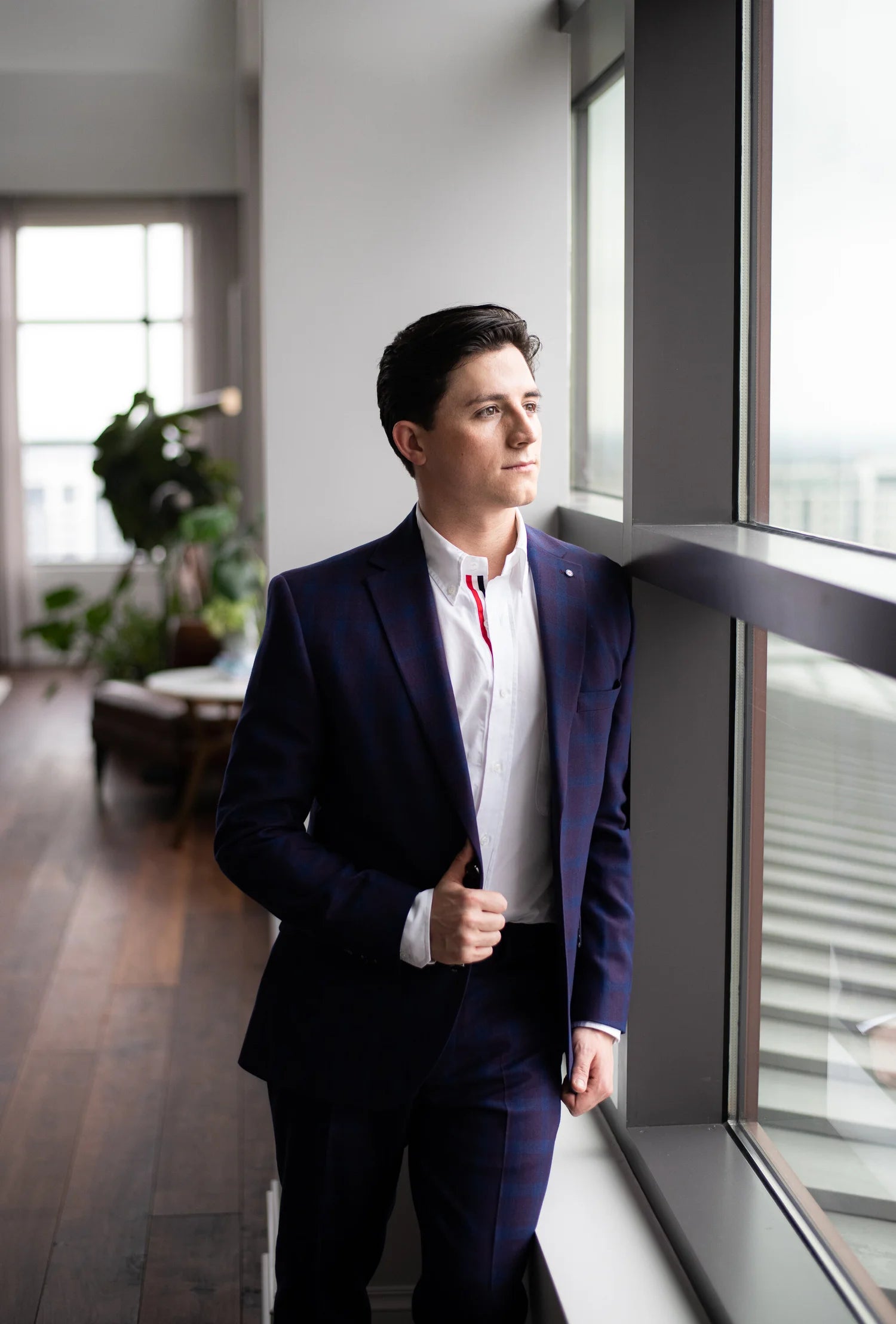 Man in a suit standing by a window in an office setting